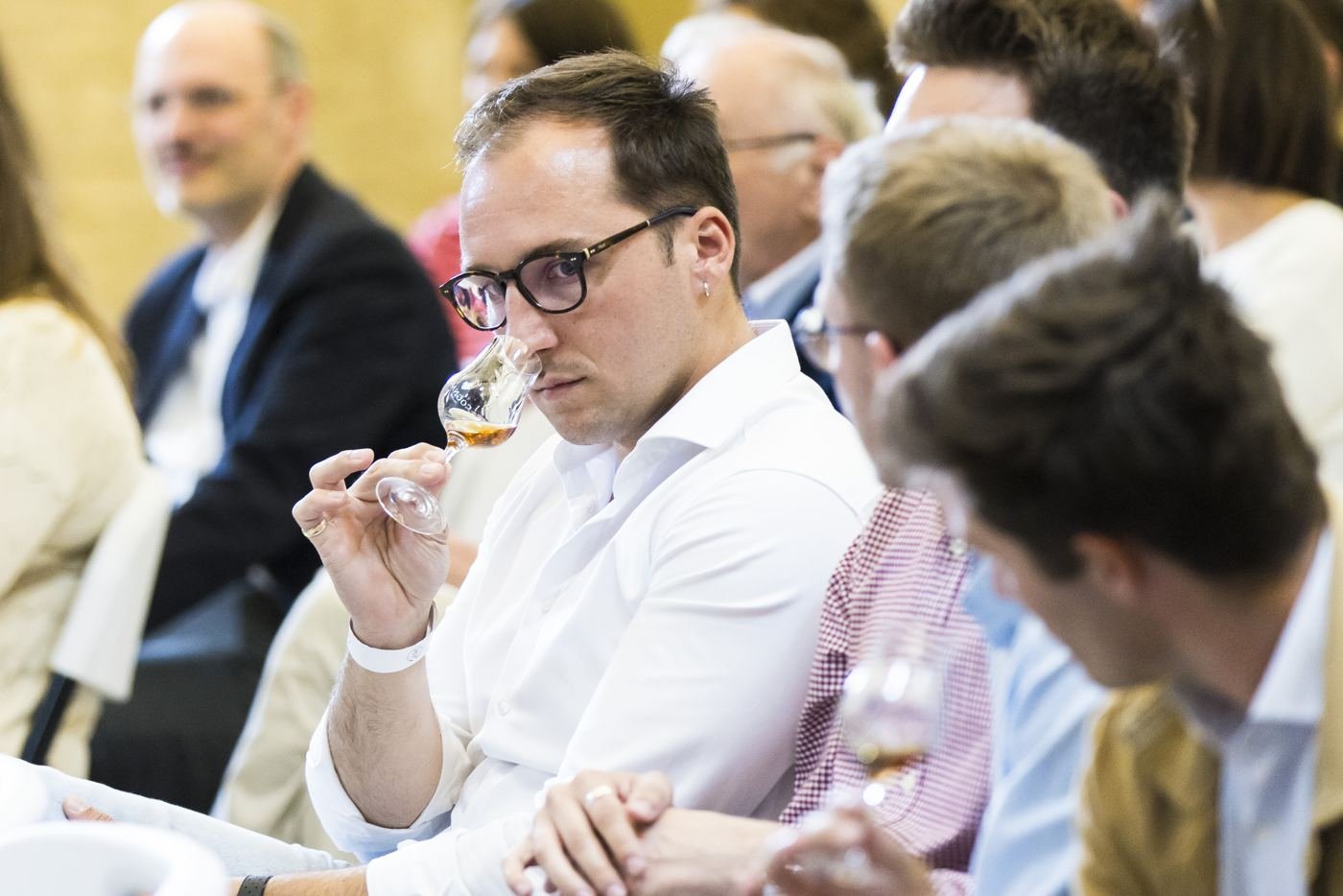 Dans le public, un spectateur hume son verre